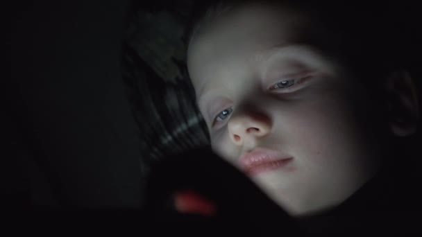 Enfant garçon de 7 ans utilisant un smartphone la nuit au lit — Video