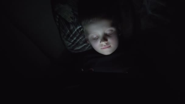 Niño de 7 años usando smartphone por la noche en la cama — Vídeo de stock