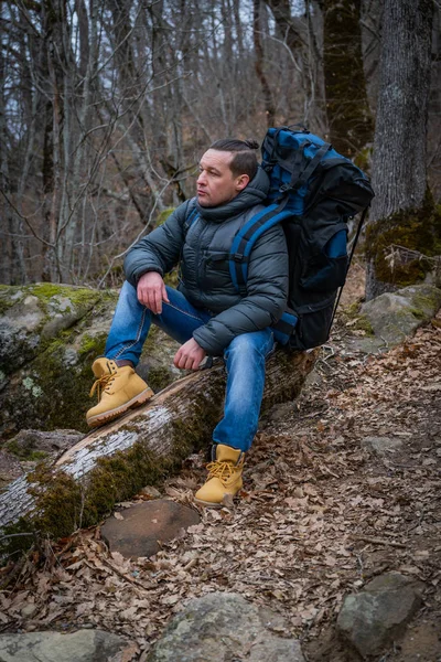 Caminante viajero se sienta en un árbol viejo en un denso bosque de otoño — Foto de Stock