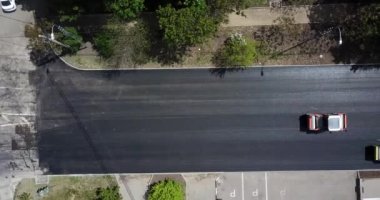 İnşaatın asfaltlanmasının havadan aşağı görüntüsü ticari tamir ekipmanları yol sıkıştırma makinesiyle çalışıyor. Yeni ve eski yol yüzeyi arasındaki karşıtlık.