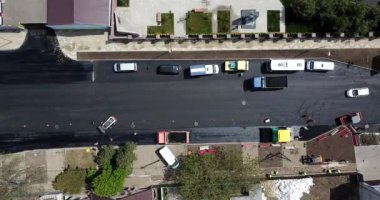 İnşaatın asfaltlanmasının havadan aşağı görüntüsü ticari tamir ekipmanları yol sıkıştırma makinesiyle çalışıyor. Yeni ve eski yol yüzeyi arasındaki karşıtlık.