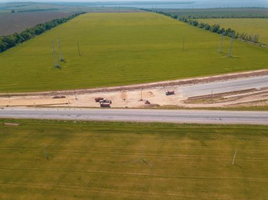 Otoyola yakın bir inşaat alanında, makineler, buldozer ve kazılar var. 4K video, yukarıdan aşağıya görünüm.