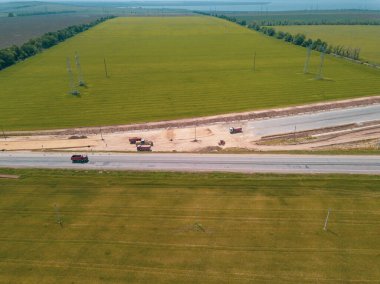 Otoyola yakın bir inşaat alanında, makineler, buldozer ve kazılar var. 4K video, yukarıdan aşağıya görünüm.