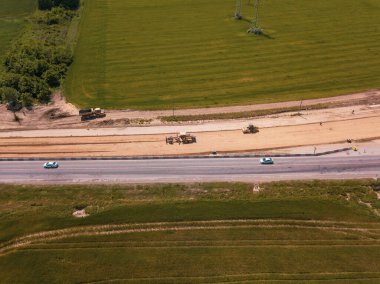 Otoyola yakın bir inşaat alanında, makineler, buldozer ve kazılar var. 4K video, yukarıdan aşağıya görünüm.