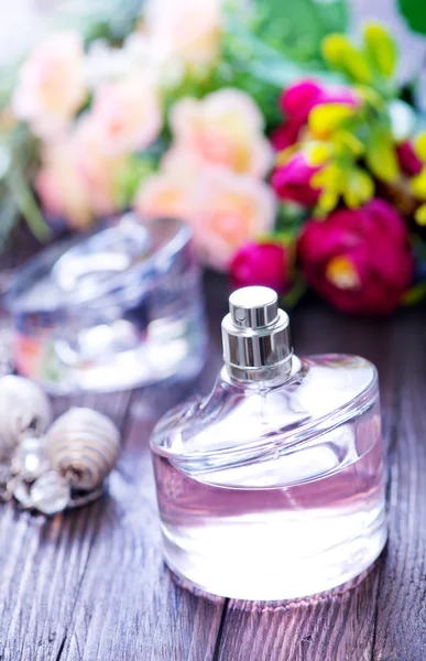 Perfume y flores en la mesa — Foto de Stock