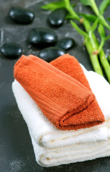 Handdoeken, zwarte stenen en bamboe op een tabel wissen — Stockfoto