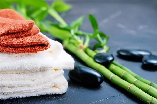 Clear towels, black stones and bamboo on a table — Stock Photo, Image