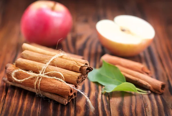 Apples with cinnamon on wooden table — Stock Photo, Image