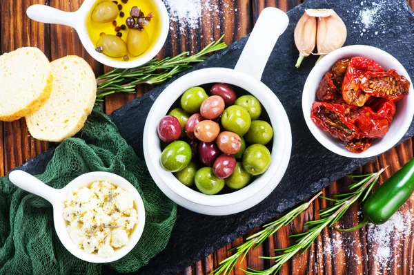 Оливки, сыр и сухие помидоры на деревянном столе — стоковое фото
