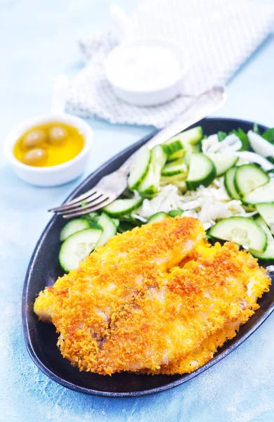 Fried fish on plate and on a table — Stock Photo, Image