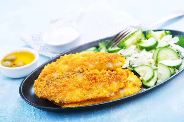 Fried fish on plate and on a table — Stock Photo, Image