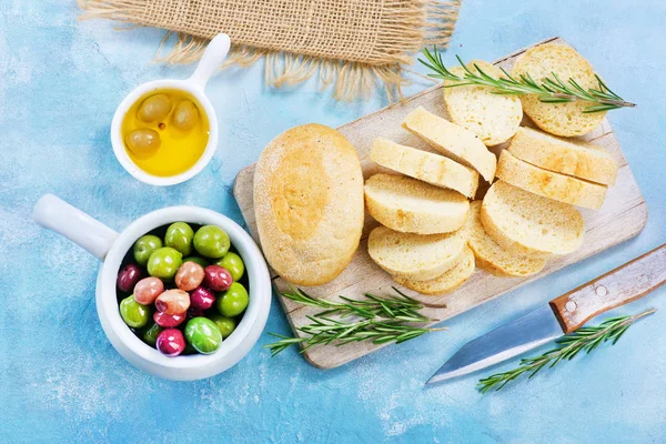 Оливки и свежий хлеб на столе — стоковое фото