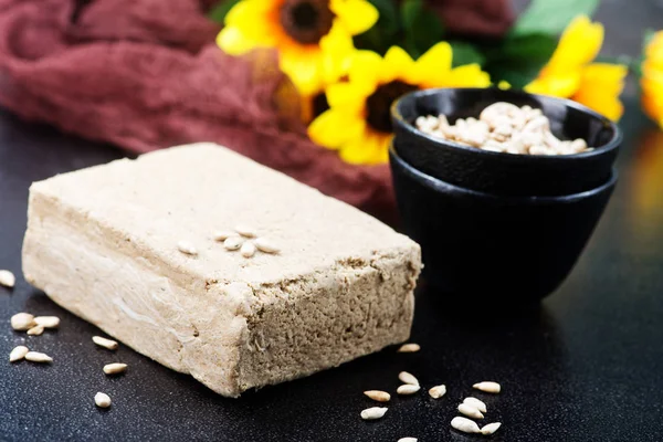 Halva con girasoles sobre mesa negra —  Fotos de Stock