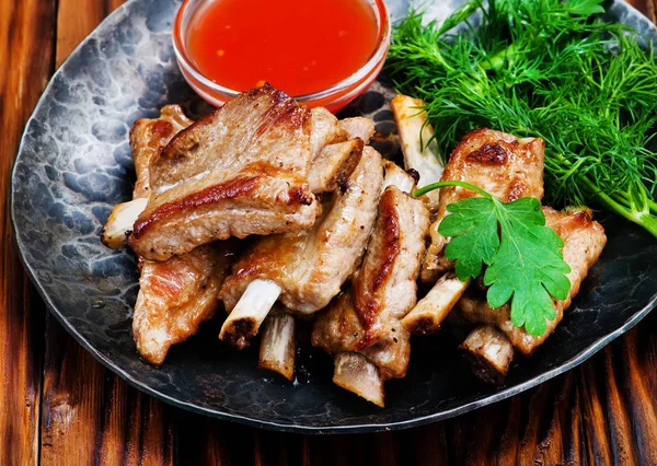 Fried meat on black plate — Stock Photo, Image