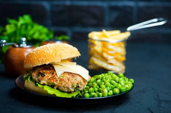 Hamburguesa y legumbre en plato negro — Foto de Stock