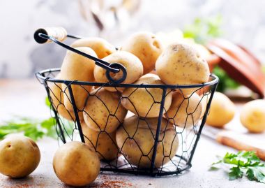 raw potato in metal basket and on a table clipart