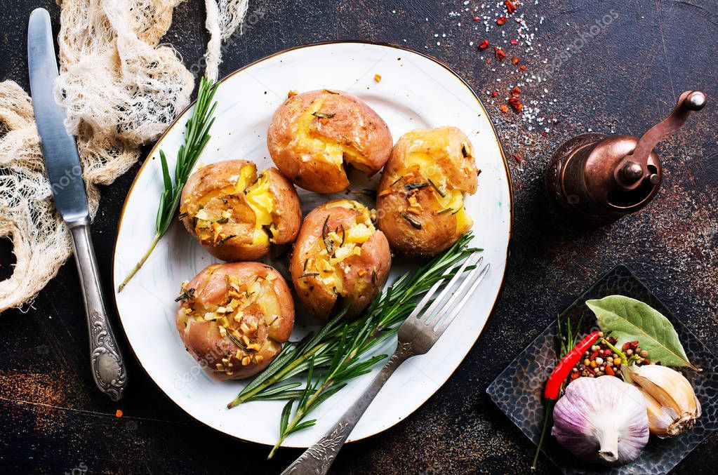 baked potatoes with spices and rosemary on dark background 