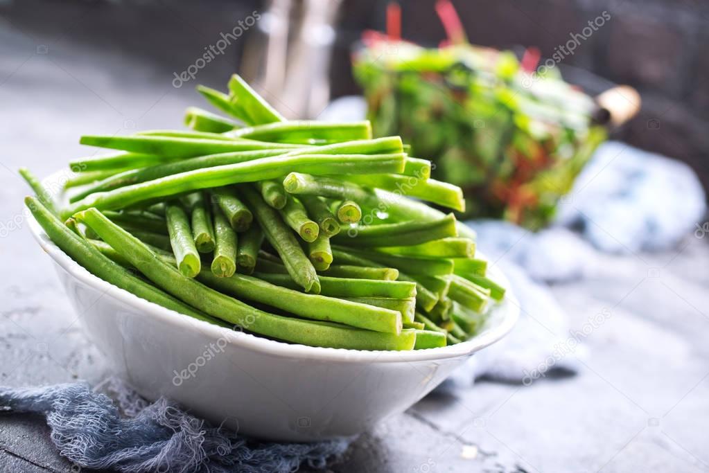 green beans in bowl and fresh leaves of mangold on table 