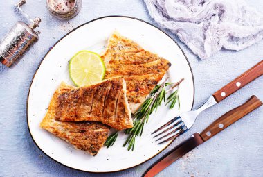 limon ve biberiye beyaz plaka üzerinde kızarmış balık 