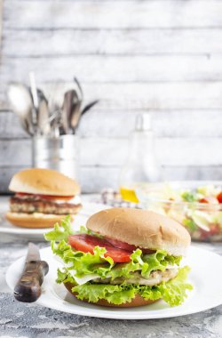 Tavuk burgeri beyaz tabakta kapanıyor. Hamburger, peynir, marul, pastırma, domates ve beyaz sos.. 