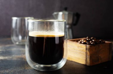 Masanın üzerinde cam bir kuo ile kahve içiyorum.