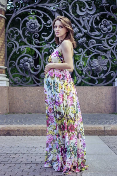 Zwangere vrouw op een stoep in de buurt van een gesmede hek — Stockfoto