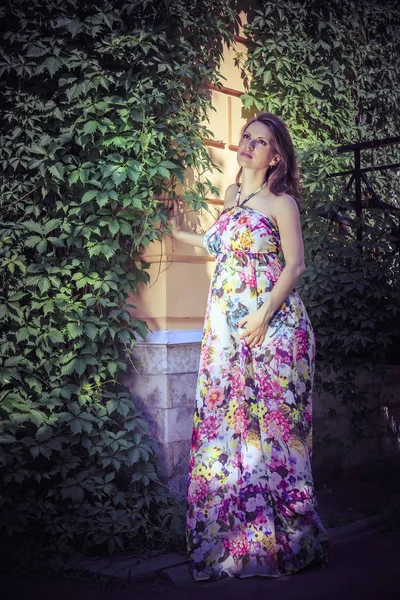 Pregnant woman on the corner of a house crooked with ivy — Stock Photo, Image