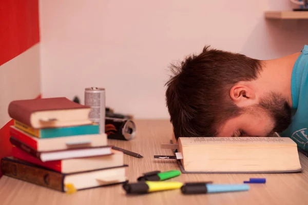 Student passed out tired in the middle of a large book while studying