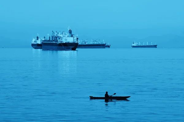 Buque de carga en mar y canoa al amanecer — Foto de Stock