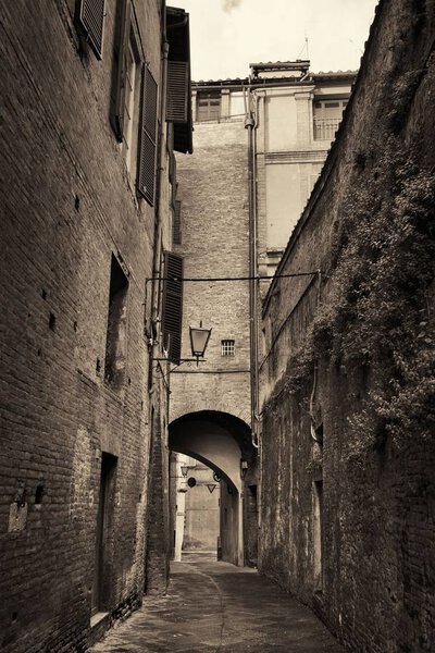 Street view with old buildings and archway in Siena, Italy
