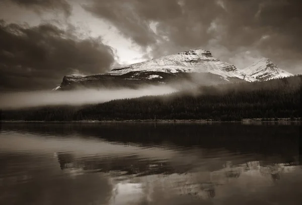Montanha coberta de neve e nevoeiro com lago — Fotografia de Stock