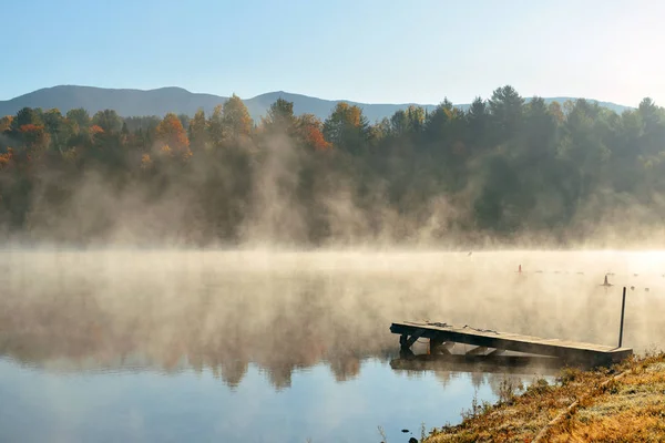 Озеро в тумане с осенней листвой — стоковое фото