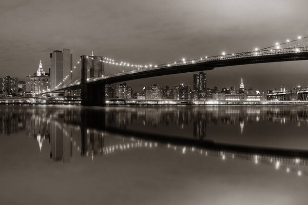 Manhattan Downtown urban view with Brooklyn bridge at night with reflections in BW