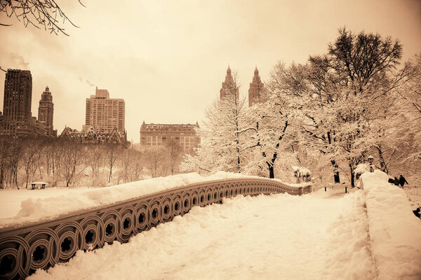 Central Park winter with skyscrapers and Bow Bridge in midtown Manhattan New York City