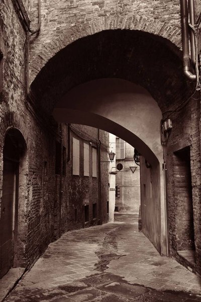 Street view with old buildings and archway in Siena, Italy.