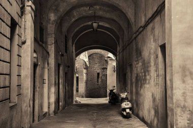 Siena, İtalya 'da eski binalar ve kemerli sokak manzarası.
