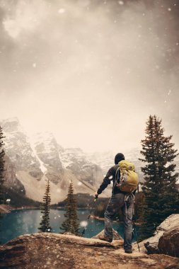 Moraine Gölü 'ndeki yürüyüşçü kar yağışlı bir günde Kanada' daki Banff Ulusal Parkı 'nın karlı tepesinde