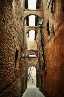 Siena, İtalya 'da eski binalar ve kemerli sokak manzarası.