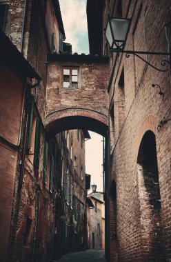 Siena, İtalya 'da eski binalar ve kemerli sokak manzarası.