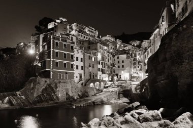 Riomaggiore rıhtımı siyah beyaz manzaralı Cinque Terre 'de geceleri binalar, İtalya.