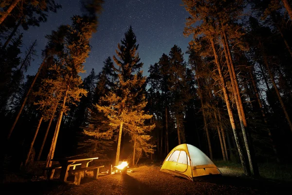 Camping under stars with bonfire and tent in Banff National Park