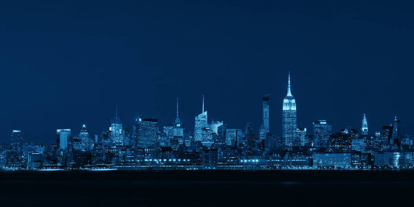 New York City midtown skyline with skyscrapers over Hudson River viewed from New Jersey at night