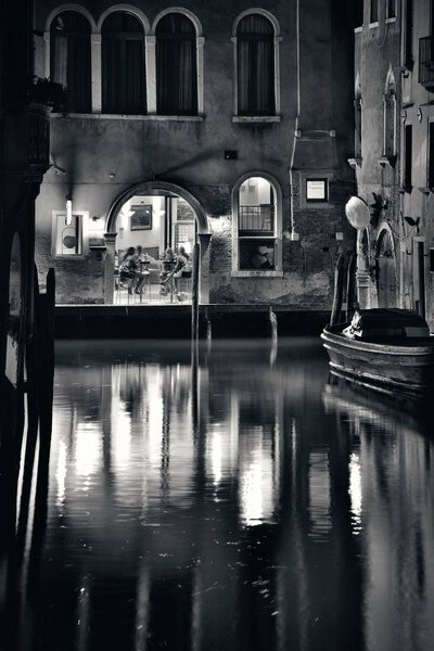 Venice canal view at night with historical buildings and reflections. Italy.
