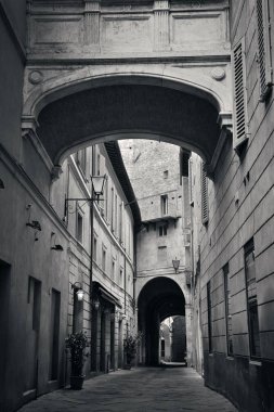 Siena, İtalya 'da eski binalar ve kemerli sokak manzarası.