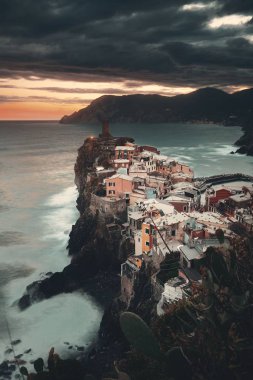 Vernazza 'da renkli bir gün batımı Cinque Terre, İtalya' da kayalar üzerinde binalar.