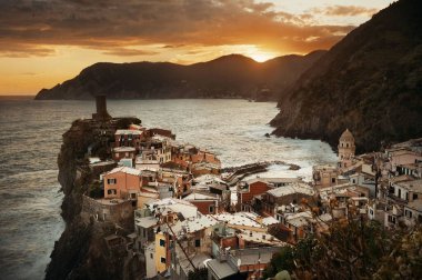 Vernazza 'da renkli bir gün batımı Cinque Terre, İtalya' da kayalar üzerinde binalar.