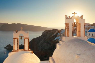 Yunanistan 'da kilise çanı ve binalarla Santorini ufuk çizgisi günbatımı.