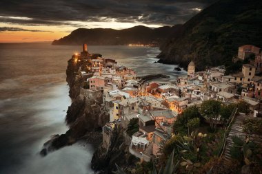Vernazza 'da renkli bir gün batımı Cinque Terre, İtalya' da kayalar üzerinde binalar.