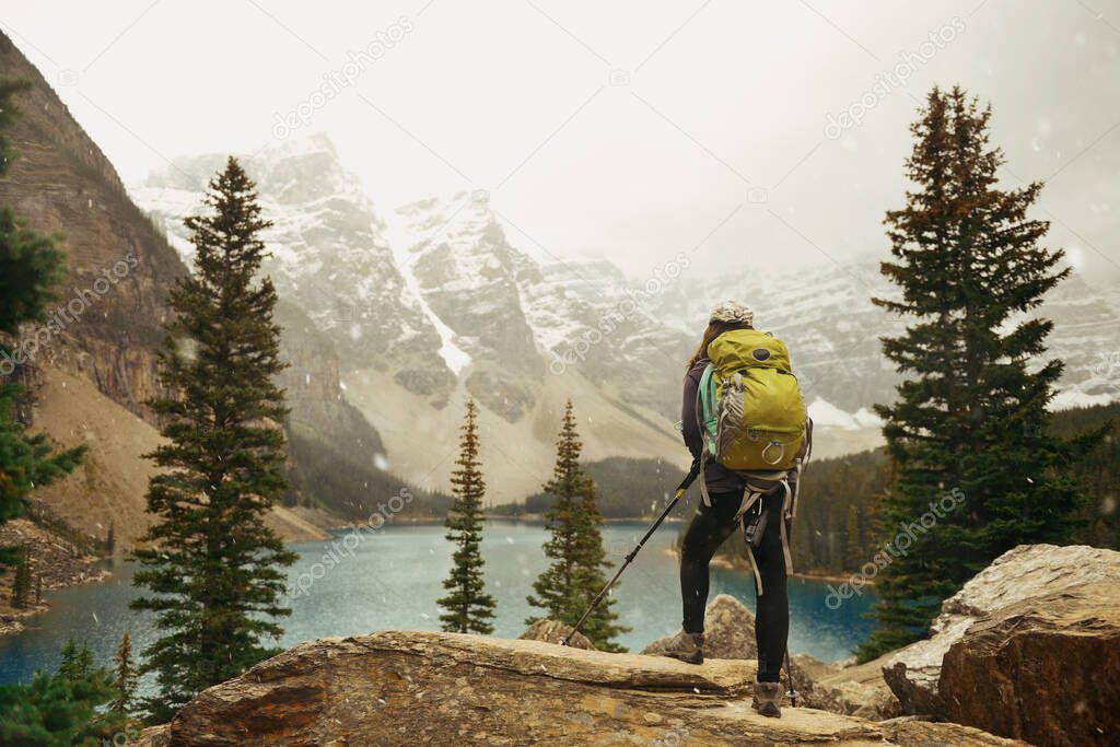 Hiker in Moraine Lake with snow capped mountain of Banff National Park in Canada in a snowing day