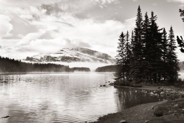 Kanada 'daki Banff Ulusal Parkı' nda kar dağı ve su yansıması olan iki Jack Gölü.